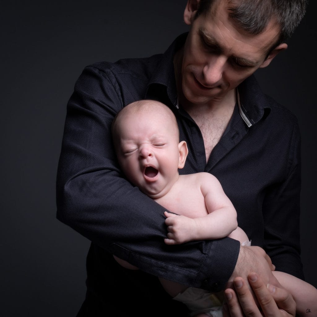 père portant son bébé dans les bras en studio de photographie